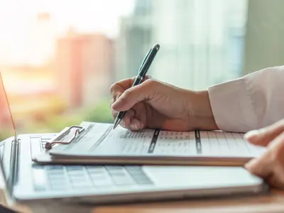 white coat filling out forms, laptop on table