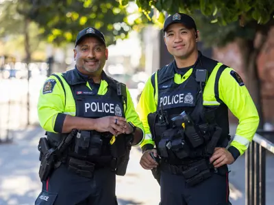 Two LPS Foot Patrol Officers, in florescent shirts, standing on sidewalk