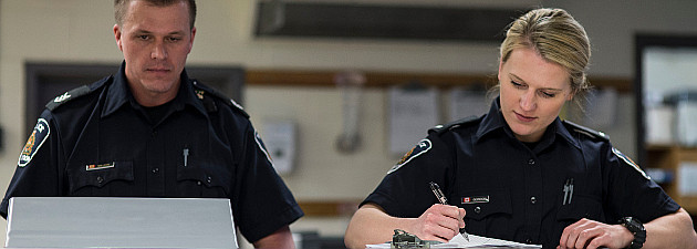 Two officers working at cell intake booking desk