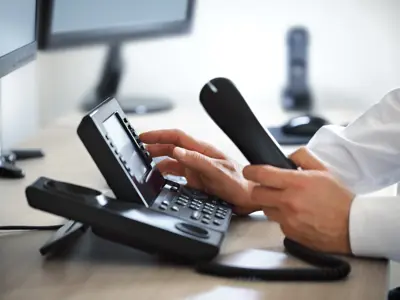 man at office desk dialing phone