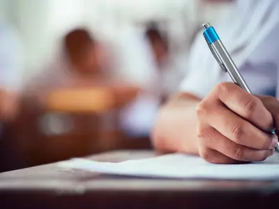 blurred out male writing test at desk